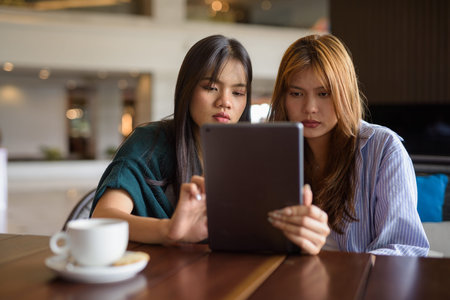 Two young Asian woman sitting together in cafe restaurantの写真素材
