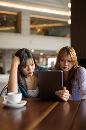 Two young Asian woman sitting together in cafe restaurantの写真素材