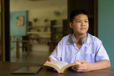 Thai Student in School Uniform Studying in Library Reading Bookの写真素材