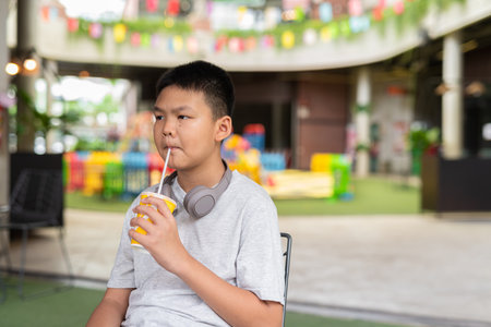 Young Asian teenager boy drinking soft drink outdoorsの写真素材