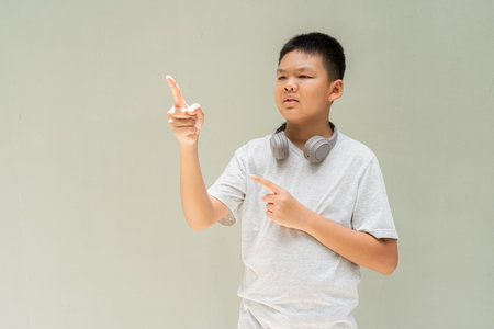 Thai Teenager Boy Portrait Against Plain Wall in Natural Lightの写真素材