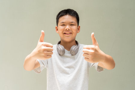 Thai Teenager Boy Portrait Against Plain Wall in Natural Lightの写真素材