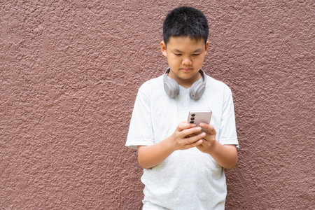 Thai Teenager Boy Portrait Against Plain Wall in Natural Lightの写真素材