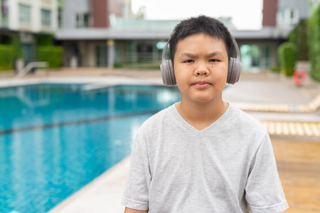 Teenage Boy at Poolside During Summer Listening Music With Headphonesの写真素材