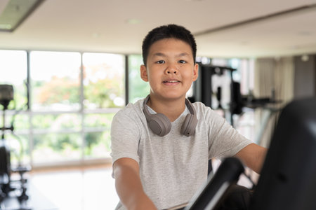 Young Asian Teen Boy Working Out on Exercise Bikeの写真素材