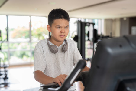 Young Asian Teen Boy Working Out on Exercise Bikeの写真素材