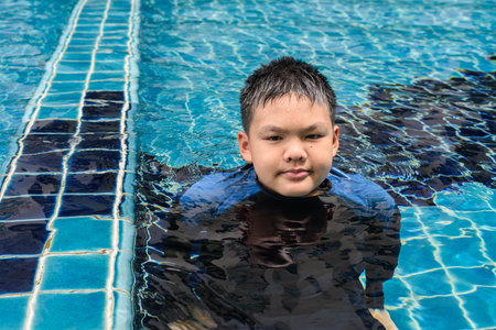 Teenage boy ready to swim in swimming pool during summerの写真素材