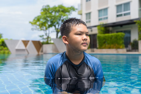 Teenage boy ready to swim in swimming pool during summerの写真素材