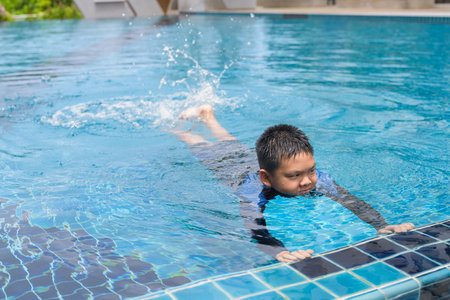Teenage boy ready to swim in swimming pool during summerの写真素材