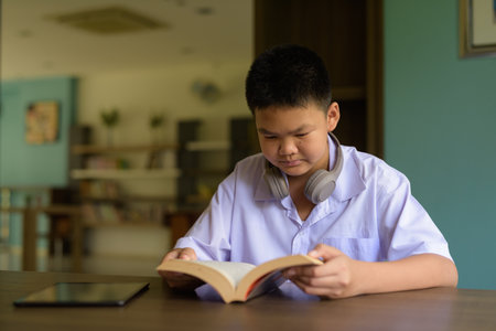 Thai Student in School Uniform Studying in Library Reading Bookの写真素材