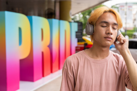 Prdie portrait of handsome gay man listening music with headphones outdoorsの写真素材