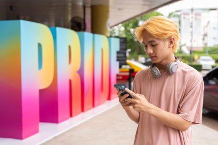 Young Asian gay man using phone during pride festivalの写真素材