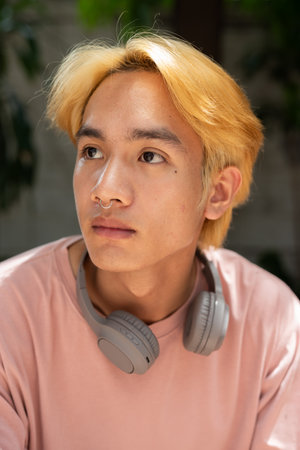 Face of young handsome teenager man sitting and thinking in cityの写真素材