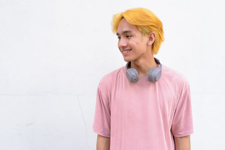 Thai gay teen man with pink shirt and septum ring against white background