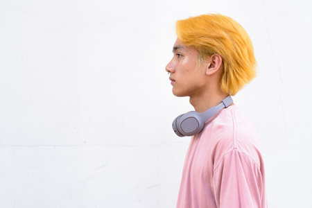 Thai gay teen man with pink shirt and septum ring against white backgroundの写真素材