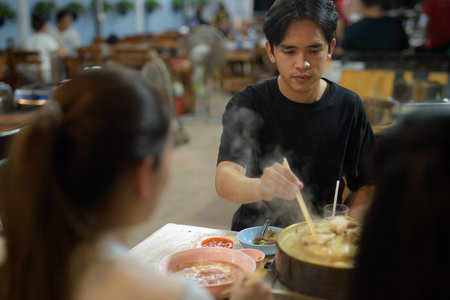 Friends eating Thai Food BBQ Grill Mu Kratha at nightの写真素材