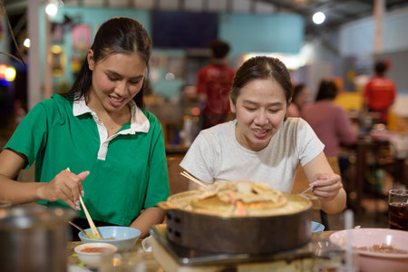 Friends eating Thai Food BBQ Grill Mu Kratha at nightの写真素材
