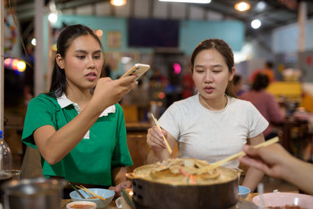 Friends eating Thai Food BBQ Grill Mu Kratha at nightの写真素材