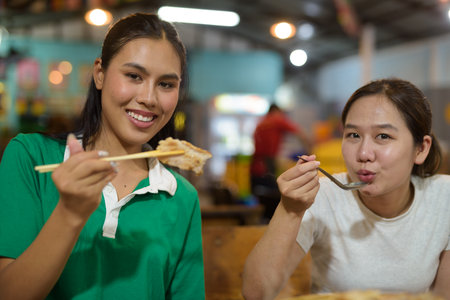 Friends eating Thai Food BBQ Grill Mu Kratha at nightの写真素材