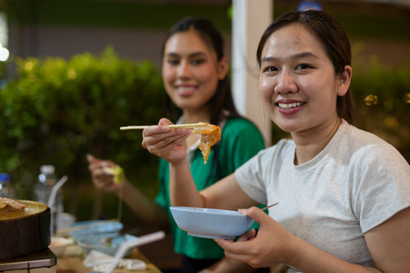 Friends eating Thai Food BBQ Grill Mu Kratha at nightの写真素材