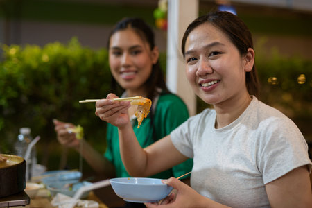 Friends eating Thai Food BBQ Grill Mu Kratha at nightの写真素材