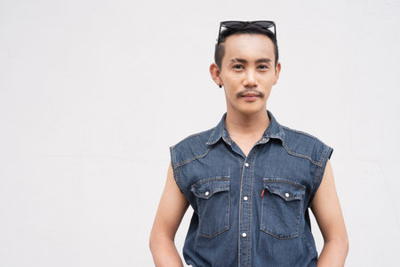 Portrait of nonbinary genderfluid young Asian gay man against white wall