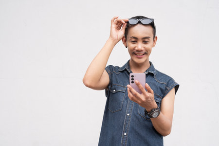 Portrait of nonbinary genderfluid young Asian gay man against white wallの写真素材