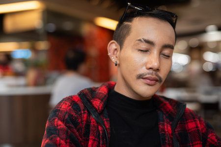 Portrait of nonbinary genderfluid young Asian gay man relaxing indoors