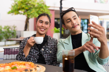 Happy friends outdoors eating pizza together outdoors in cafe restaurantの写真素材