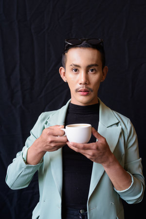 Portrait of nonbinary genderfluid young Asian gay man against dark backgroundの写真素材