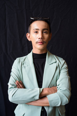 Portrait of nonbinary genderfluid young Asian gay man against dark background