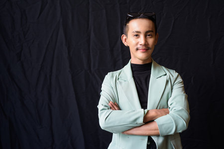 Portrait of nonbinary genderfluid young Asian gay man against dark backgroundの写真素材