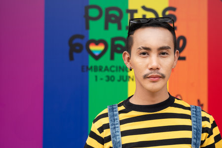 Portrait of confident nonbinary genderfluid young Asian gay man against pride flag backgroundの写真素材