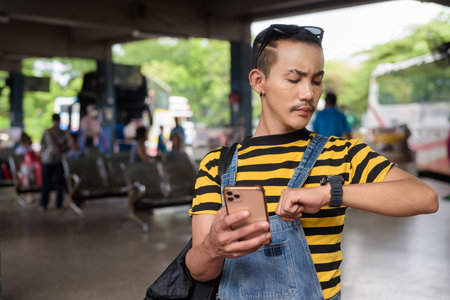 Cute nonbinary genderfluid young Asian gay tourist man in bus terminalの写真素材