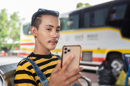 Cute nonbinary genderfluid young Asian gay tourist man in bus terminalの写真素材