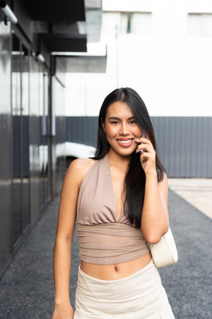 Modern Asian Woman Using Phone Outdoors in City During Dayの写真素材