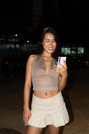 Young Asian Woman Using Smartphone at Night in Cityの写真素材