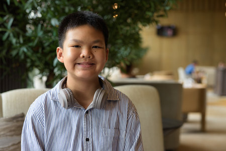 Portrait of Thai boy sitting at cafe with headphonesの写真素材
