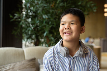 Portrait of Thai boy sitting at cafe with headphonesの写真素材