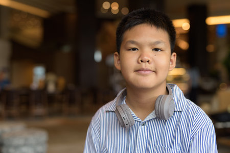 Portrait of Thai boy sitting indoors at restaurant aloneの写真素材