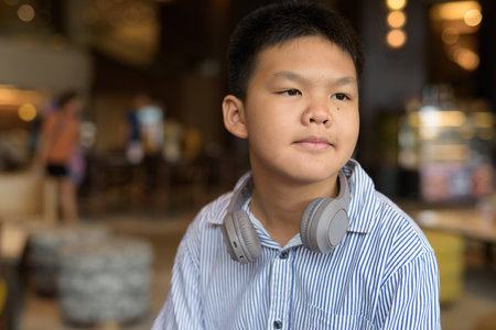 Portrait of Thai boy sitting indoors at restaurant aloneの写真素材