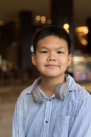 Portrait of Thai boy sitting indoors at restaurant aloneの写真素材