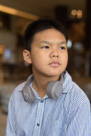 Portrait of Thai boy sitting indoors at restaurant aloneの写真素材