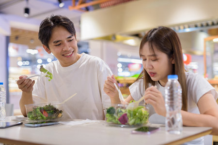 Young couple eating salad together in restaurantの写真素材