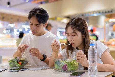 Young couple eating salad together in restaurantの写真素材