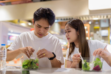 Young couple eating salad together in restaurantの写真素材
