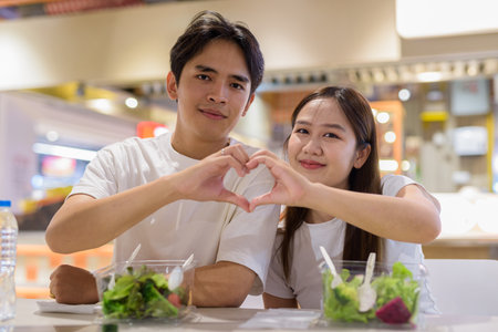 Young couple eating salad together in restaurantの写真素材