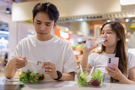 Young couple eating salad together in restaurantの写真素材
