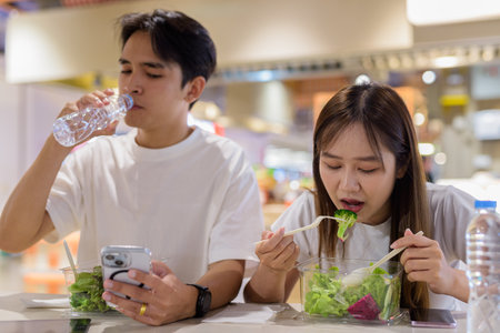 Young couple eating salad together in restaurantの写真素材