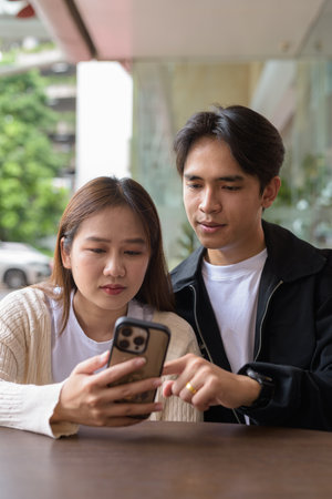 Young couple using mobile phone together outdoorsの写真素材